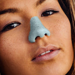 Load image into Gallery viewer, Nöz reef safe SPF sunscreen in teal on woman&#39;s nose.
